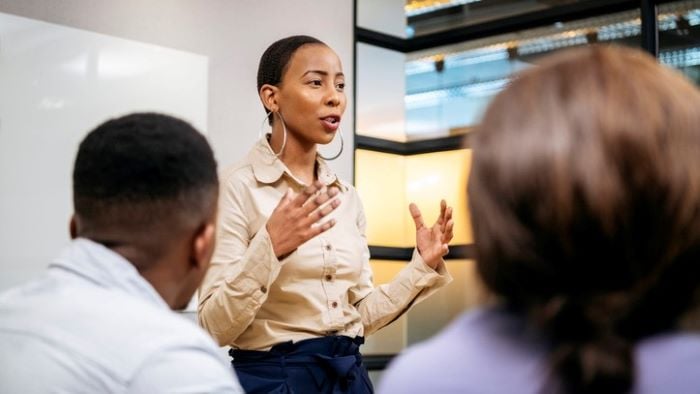 A business leader stands in front of their team