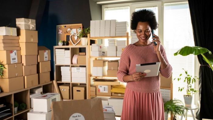 A woman speaks on phone surrounded by boxes