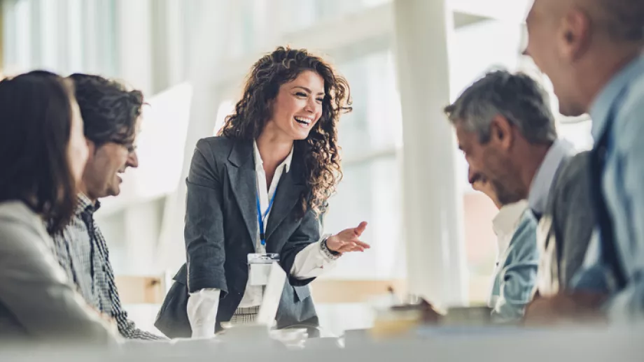 Woman speaks to colleagues across table