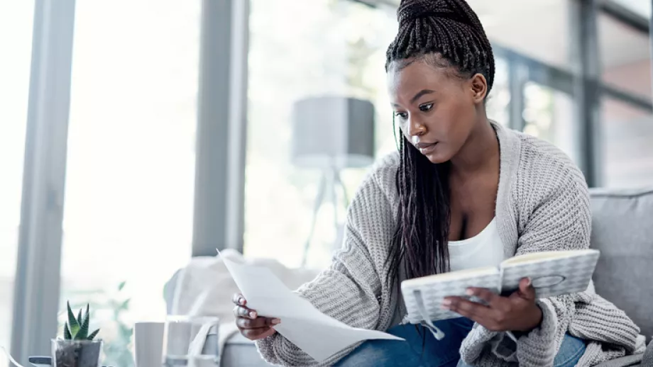 A woman sits at a table with notebook and paper